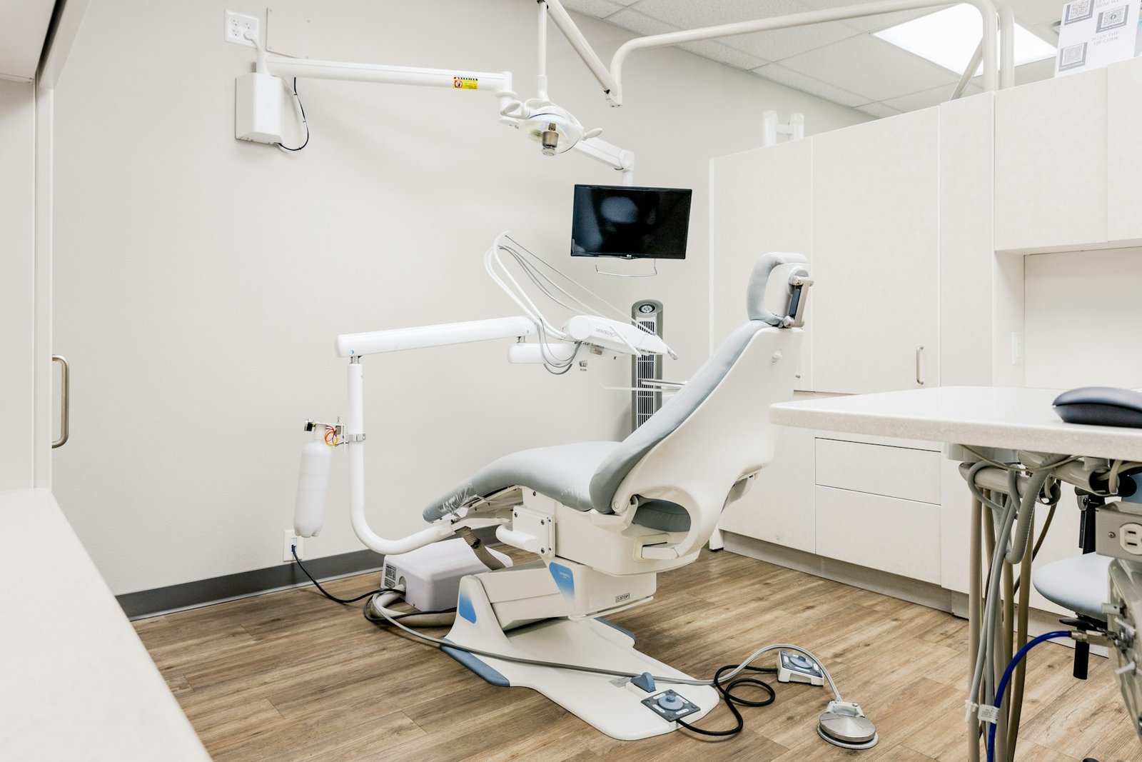 Heller Behandlungsraum mit Stuhl und Instrumenten.